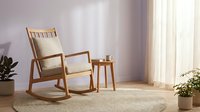 Wooden rocking chair with beige cushion in minimalist room with natural light, potted plants, and sheer curtains for interior design and home decor projects.
