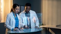 Two diverse medical professionals examining holographic spine and brain scans on futuristic digital display in modern healthcare facility.