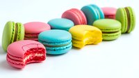 Colorful French macarons in vibrant shades arranged on white background. Sweet pastry dessert cookies with cream filling for bakery menu design.