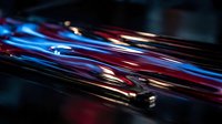 Abstract high-speed motion with glowing neon light trails in blue, red, and gold streaks across dark background. Suitable for technology, digital innovation, and modern design projects.