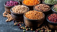Colorful variety of raw legumes and pulses in rustic wooden bowls on dark background. Healthy vegan protein source, traditional cooking ingredients.