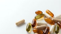 Colorful vitamin and supplement capsules scattered on white background for health and wellness concepts.