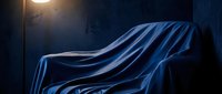 Sleek car covered in flowing blue fabric under dramatic streetlight, revealing silhouette and curves for automotive advertising and design concepts.