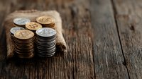 Stacks of gold and silver cryptocurrency coins on rustic burlap fabric against dark wooden background, dramatic lighting creates financial atmosphere.