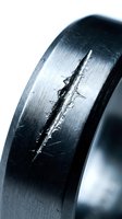 Close-up of damaged metal ring with deep crack on brushed steel surface showing wear and structural failure for industrial safety concepts.
