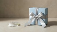 Elegant light blue gift box with silver satin ribbon bow on neutral beige background for special occasions and celebrations.