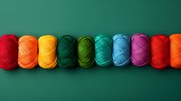 Colorful yarn balls arranged in rainbow spectrum on dark green background, including red, orange, yellow, green, blue and pink shades. For crafting and knitting projects.