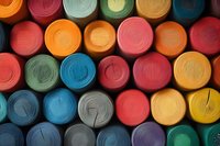 Colorful yarn spools arranged in rows creating vibrant pattern of circles. Close-up view of multicolored textile threads showing texture and crafting materials.
