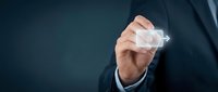 Businessman in dark suit holding transparent glass cube with glowing light effect against blue background for business innovation concepts.