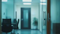 Modern office interior with glass doors and empty corridor in blue tones, showing contemporary workspace design with minimalist aesthetic and natural lighting.