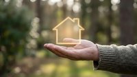 Hand holding glowing house symbol representing home protection, real estate investment, property insurance and mortgage security concept.