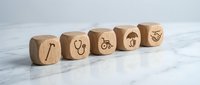 Wooden cubes with disability and accessibility icons including cane, wheelchair, umbrella and heart symbols representing inclusive design concepts.