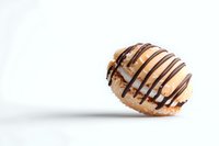 Fresh cream-filled donut with chocolate drizzle on white background, floating with soft shadow. Appetizing pastry for bakery and dessert menus.