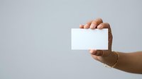 Male hand with medium skin tone holding blank white card against neutral background, suitable for business presentations, marketing campaigns, and promotional designs.