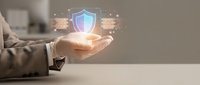 Businessman hand holding glowing shield icon with digital network code, representing cybersecurity, data protection, and secure technology solutions for business.
