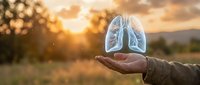 Hand holding glowing lungs hologram at sunset symbolizing respiratory health, medical care and breathing wellness in natural outdoor setting.