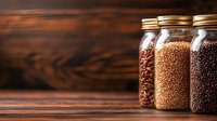 Glass jars filled with different types of coffee beans and grains on wooden background with copy space, warm lighting creates cozy atmosphere for cafe menu.
