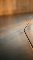 Close-up view of modern ceramic floor tiles with warm lighting creating soft shadows and depth for interior design and home renovation projects.