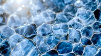 Macro view of blue agate crystal structure showing natural mineral pattern with hexagonal cells and translucent surface texture in cold tones.