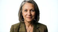 Professional mature Hispanic businesswoman with gray hair in olive green blazer smiling confidently on white background for corporate headshot photography.