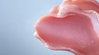 Soft pink rose petal with delicate water droplets and morning dew in macro close-up against blurred light background, creating romantic and gentle atmosphere.
