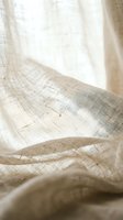 Natural linen fabric with soft folds and gentle lighting creating organic textures and shadows for home decor and textile design projects.