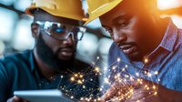 African American engineers analyzing digital network visualization on tablet, wearing hard hats and safety glasses in industrial setting with glowing data connections.