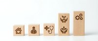 Wooden blocks with healthcare and wellness icons arranged in ascending order representing growth in medical services and patient care solutions.