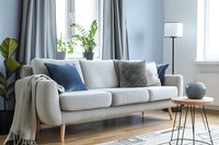Modern white sofa with blue and gray pillows in bright living room with houseplants and minimalist decor for interior design inspiration.