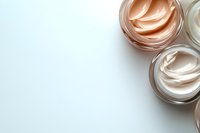 Luxurious face cream jars with peach and white moisturizer on light background. Minimal beauty composition with copy space for skincare and cosmetic products.