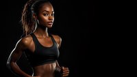 Athletic African American woman in black sports bra against dark background, showing toned muscles and determined expression during fitness workout.