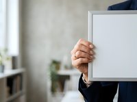 Mature adult male professional holding blank white board in modern office environment for corporate messaging and business communication.