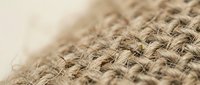 Natural burlap fabric texture with woven jute fibers in beige and brown tones, close-up macro photography showing organic textile pattern for rustic design projects.