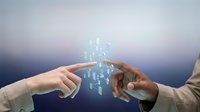 Young diverse professionals exchanging digital holographic city skyline between hands, representing urban development, smart technology, and collaborative business innovation solutions.