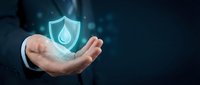 Businessman hand holding glowing water drop shield icon, representing environmental protection, sustainability, and eco-friendly business solutions for corporate campaigns.