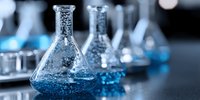 Laboratory glassware with blue chemical solutions on dark surface for scientific research and experimentation in modern chemistry lab setting.