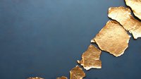 Torn pieces of gold leaf paper arranged diagonally on dark blue background creating abstract minimalist composition with dramatic contrast and texture.