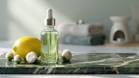 Lemon essential oil in glass dropper bottle surrounded by fresh lemons and chamomile flowers on marble surface for aromatherapy and wellness.