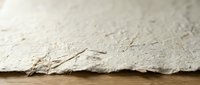 Close-up of white asbestos insulation material showing fibrous texture and layered structure on wooden surface for industrial safety and construction documentation.