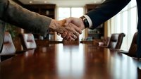Business handshake between two professionals in modern conference room sealing deal or partnership agreement in corporate office setting.