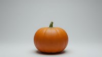 Fresh orange pumpkin with green stem isolated on white background for autumn harvest decorations and seasonal design projects.