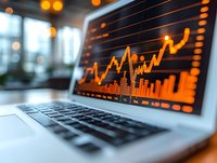 Orange glowing stock market chart displayed on laptop screen with trading data and financial analytics, blurred office background with bokeh lights.