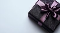 Black glittery gift box wrapped with elegant purple satin ribbon bow on light background, festive present for special occasion or luxury holiday celebration.