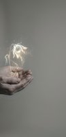 Cupped hands holding glowing magical flower with sparkling light effects on neutral background for fantasy and spiritual concepts.
