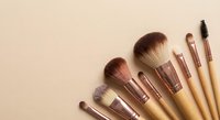 Professional makeup brushes with rose gold ferrules and natural bristles arranged on neutral beige background for beauty and cosmetics applications.