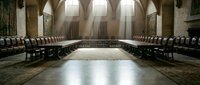 Empty cathedral interior with wooden chairs arranged in rows along stone walls, featuring arched ceilings and natural light from windows, suitable for religious and architectural design projects.