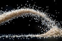 White sugar crystals scattered in dynamic wave pattern against black background, creating elegant flowing motion effect with sparkling granules.