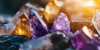 Colorful healing crystals and mineral stones in natural sunlight with purple amethyst, citrine, and quartz formations showing raw crystalline structure.