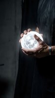Businessman holding glowing crystal ball with clock face showing time management and future planning concepts in dark office environment.