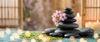 Zen spa stones balanced with pink orchid flowers in serene wellness center setting for meditation and relaxation therapy treatments.